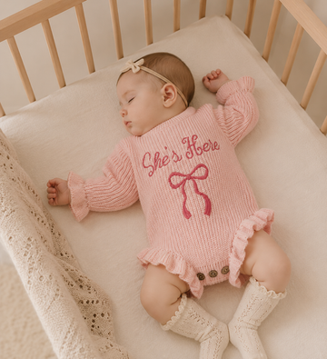 “She’s Here” Knit Baby Girl Romper – Embroidered Bow